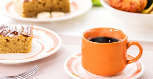 Cup of Café Bustelo Brazil with cake in the background