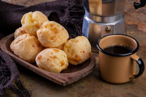 Table with delicious Pão de Queijo, a mug of Cafe Do Ponto Exportacao coffee and a traditional coffee maker