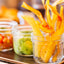 Mariquitas Plantain Chips Con Ajo served in glass jar with salsa and guacamole, snack or appetizer, delicious and colorful